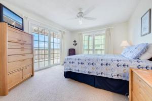 a bedroom with a bed and a dresser and windows at The Ferdinando at Ships Watch in Duck