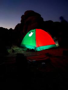 un parapluie vert et rouge dans l'obscurité dans l'établissement Wadi Rum Sights Camp, à Wadi Rum