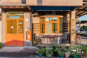 a building with an orange door and a table and chairs at New Fox Guest House in Zhuangwei