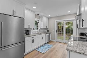 a kitchen with white cabinets and a large window at The Blue Wave Quiet & Cozy Beach Retreat in Oak Island