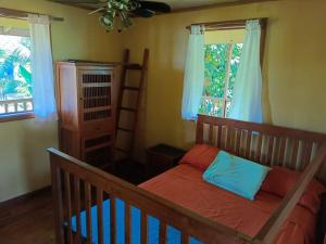 a bedroom with a bed and a crib and two windows at Casa Ylang in Bastimentos