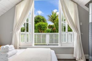 a bedroom with a large window with white curtains at Beautiful Ponsonby Villa by Zodiak Stays in Auckland