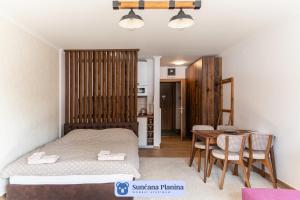 コパオニクにあるSunčana Planina - Apartmani Wombatのベッドルーム1室(ベッド1台、テーブル、椅子付)