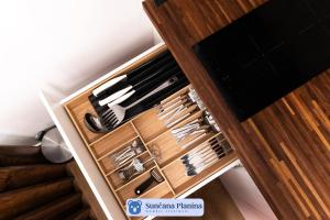 a drawer full of knives in a wooden cabinet at Sunčana Planina - Apartmani Wombat in Kopaonik