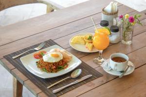 a table with two plates of food and a cup of coffee at Ora Villas Gili Meno in Gili Meno