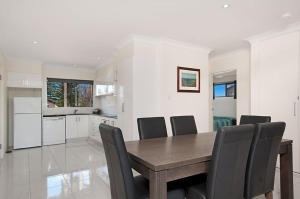 a kitchen and dining room with a wooden table and chairs at Pacific Palms 4 Unit 4, 9-11 Terrace St Evans Head in Evans Head