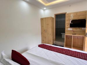 1 dormitorio con 1 cama y TV en una habitación en Sharma Farms, en Jamnagar