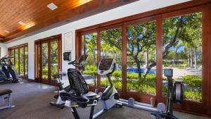 - une salle de sport avec tapis de course et matériel d'exercice devant les fenêtres dans l'établissement PLUMERIA HALE Exquisite 4BR KaMilo Home with Bikes and Beach Gear, à Waikoloa