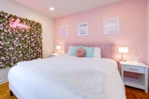 a bedroom with a white bed with a pink wall at Taylor Swift Eras Inspired Home-10 min to Broadway in Nashville