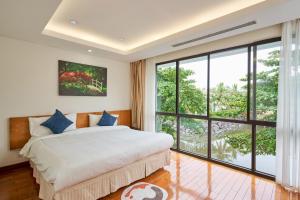 a bedroom with a bed and a large window at Ocean Sunny Villas Da Nang in Danang