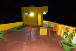 a patio with orange chairs and a yellow wall at Chez Linda Home Stay at French colony in Pondicherry