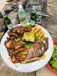 a plate of meat and vegetables with two bottles of beer at Du Già Coffee View Homestay in Làng Cac