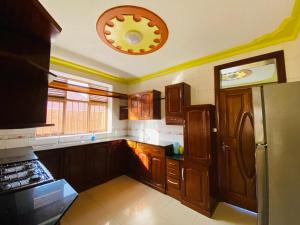 a kitchen with wooden cabinets and a ceiling at Quiet and Spacious Hidden Gem in Kigali with Breathtaking Views right by the Airport in Kigali