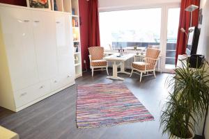 - un salon avec une table, des chaises et une grande fenêtre dans l'établissement Krabbenliebe, à Westerland