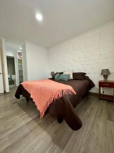 a bedroom with a large bed with an orange blanket at Cálido y espacioso departamento in Los Ángeles