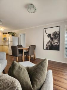 a living room with a table and a cow on the wall at Karapiro Apartment in Cambridge