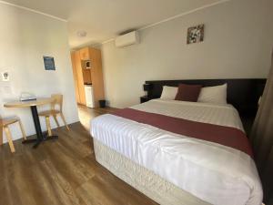 a bedroom with a large bed and a table at Ocean Inn Motel in Auckland