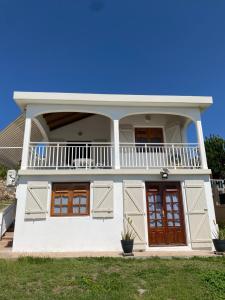 a white house with a balcony and two doors at KARIFUNA-II in Baie Mahault