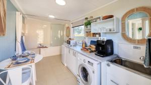 eine Küche mit einer Waschmaschine und einem Waschbecken in der Unterkunft Badger's View Farmstay Cottage in Railton