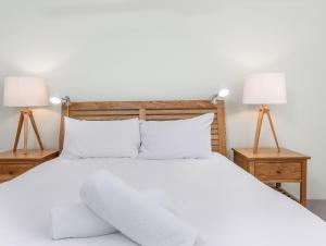 una camera con un letto bianco e 2 lampade di Stunning She Oak Lane - 2 Bedroom Apartment! a Casuarina