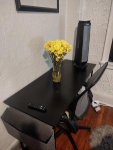 a vase of yellow flowers on a table with a tv at Clearviewpeace in Paterson