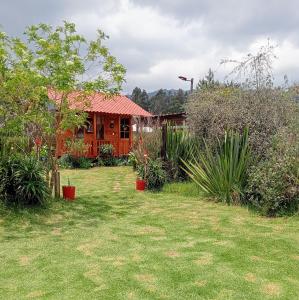 a house with a yard with plants in front of it at Cabaña Los Linos in Guasca
