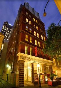 un edificio alto de ladrillo rojo con luces encendidas en Melbourne boutique hotel en Melbourne