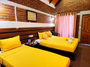 two beds in a room with yellow sheets at Cocolagoon eco Resort Nilaveli in Trincomalee
