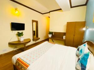 een slaapkamer met een bed, een tafel en een televisie bij Hotel Tara INN with terrace and mountain view in Shimla