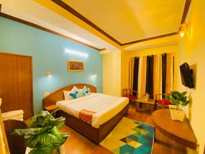 1 dormitorio con cama, mesa y TV en Hotel Tara INN with terrace and mountain view, en Shimla