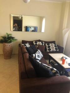 a living room with a brown couch and a mirror at Apartman Andalusie in Hurghada