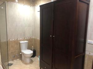 a bathroom with a toilet and a large wooden cabinet at Apartman Andalusie in Hurghada