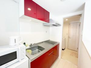 una pequeña cocina con fregadero y microondas en YOUR ROOM Kumamoto Sta little 103 Vacation STAY 75704, en Kumamoto