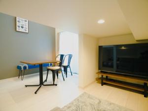 熊本的住宿－YOUR ROOM Kumamoto Sta little 205 Vacation STAY 75243，客厅配有桌椅和电视。