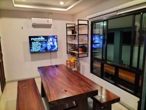 sala de estar con mesa de madera y TV en บ้านบัวหลวงกันตังเมืองเก่า, en Ban Laem Muang