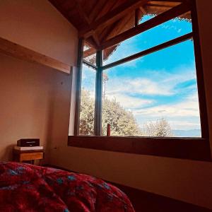 a bedroom with a large window with a view at Oakakhi Stays, Deluxe room in Rānīkhet