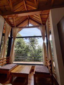 a room with a large window with benches and a balcony at Oakakhi Stays, Deluxe room in Rānīkhet