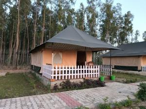 a small house with a black roof and a white fence at Pulastya Wellness Resort in Sahāranpur