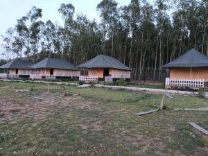 a row of houses with black roofs in a field at Pulastya Wellness Resort in Sahāranpur
