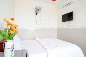 Habitación con cama y jarrón con flores en Hotel Trâm Anh 2 en Nhơn Trạch