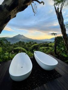 a white bath tub sitting on a deck with a tree at Black Wood Cabin in Kintamani
