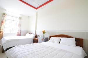 a bedroom with two white beds and a window at Hotel Trâm Anh 2 in Nhơn Trạch