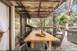 a patio with a table and chairs on a deck at Canto do Sol - 4BR Avoca Getaway in Avoca Beach