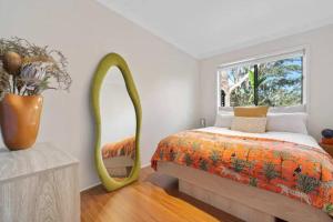 a bedroom with a bed with a mirror and a window at Canto do Sol - 4BR Avoca Getaway in Avoca Beach