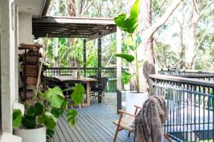 a wooden deck with a table and chairs on it at Canto do Sol - 4BR Avoca Getaway in Avoca Beach