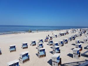 uma praia com cadeiras azuis e brancas e o oceano em Im Zentrum von Westerland gelegene Ferienwohnung mit Westbalkon und schönem Ausblick em Westerland