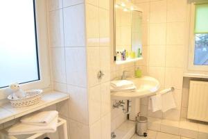 La salle de bains blanche est pourvue d'un lavabo et d'une douche. dans l'établissement Krabbenliebe, à Westerland