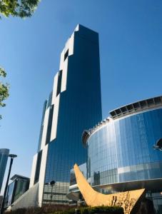 een hoog glazen gebouw met een sculptuur ervoor bij Mirae stay 67 in Seoul