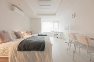Mirae stay 67 في سول: غرفة نوم بيضاء بسرير وطاولة وكراسي