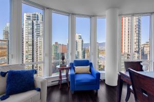 a living room with a blue chair and large windows at Breathtaking Downtown Condo with Stunning Harbor Views! in Vancouver